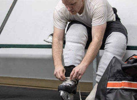 Hockey player preparing to wash shin pads in locker room, questioning can you wash hockey shin pads