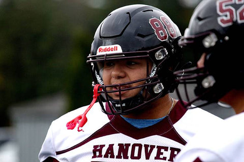 Football player adjusting chin strap for a proper fit.