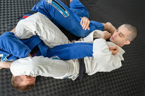 Jiu Jitsu athletes grappling on mat to illustrate the close contact sport.