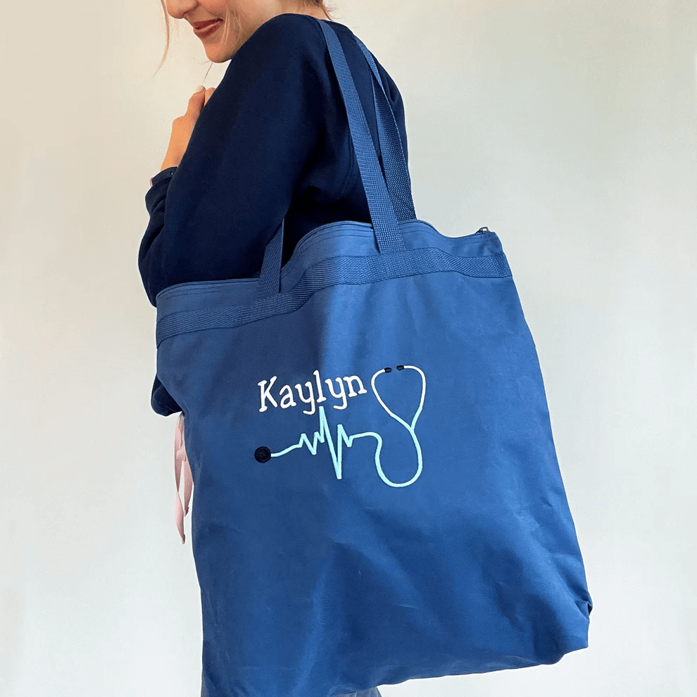 woman carrying a blue tote bag with embroidered white text on the front