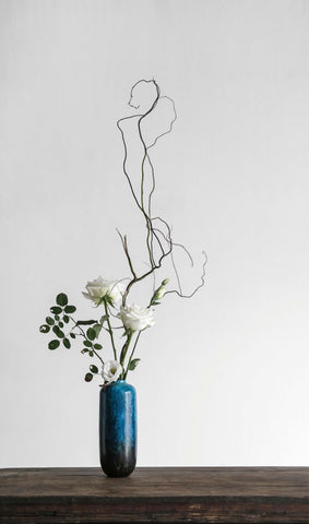 Œuvre d'art floral Ikebana moderne. Vase foncé en haute avec des végétaux épurés