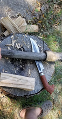using large knife and mallet to shape wooden stock for machete handle