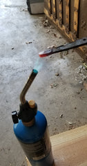 Heating up a steel blank to burn in the wooden handle for machete tang