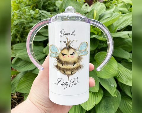 A white adult sippy cup with handles and a bee design on the front.