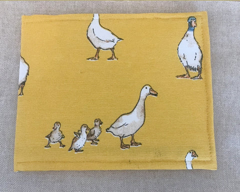 A blue badge cover with yellow fabric and images of ducks