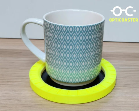 A black coaster with a neon yellow raised edge with a blue cup in the centre