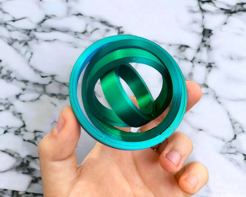 A hand holding a blue and green circular fidget toy