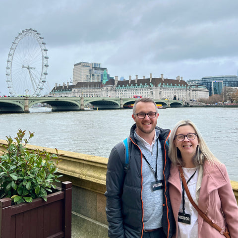 Hayley and her husband Scott stood on the outside terrace at the House of Lords, the River Thames is behind them, the London eye, Westminster Bridge and other landmarks are visible in the background.