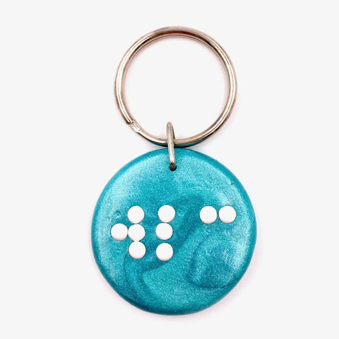 a blue clay keyring with wlc in braille
