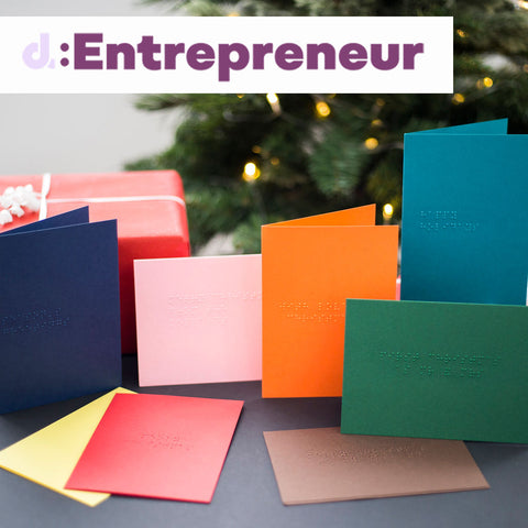 Braille Christmas cards in eight colours including red, green, pink, yellow, orange, teal, navy and chocolate with the d:Entrepreneur logo