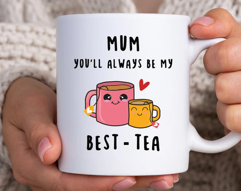 A white mug with a two tea cups, one is pink and bigger and the other is orange and smaller, it says Mum you'll always be my best-tea