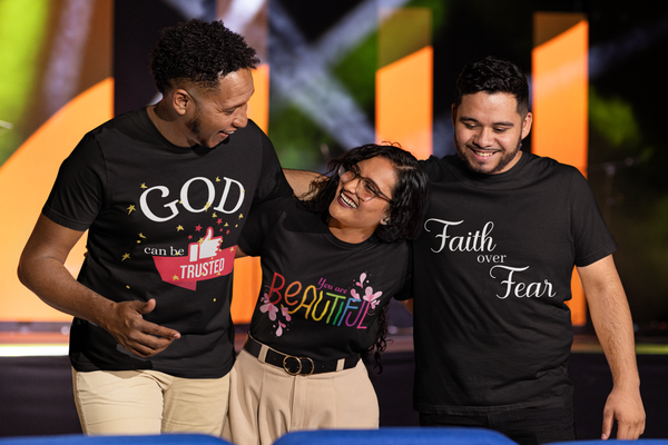 Two men and a woman in a group hug at a christian forum wearing various motivational t-shirt designs.