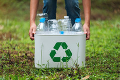 picture of a lady picking up empty plastic bottles in a plastic container