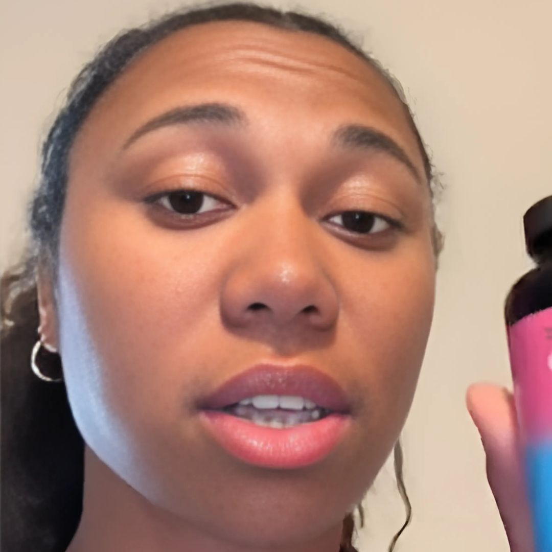 A person holding a bottle with a pink and blue label.