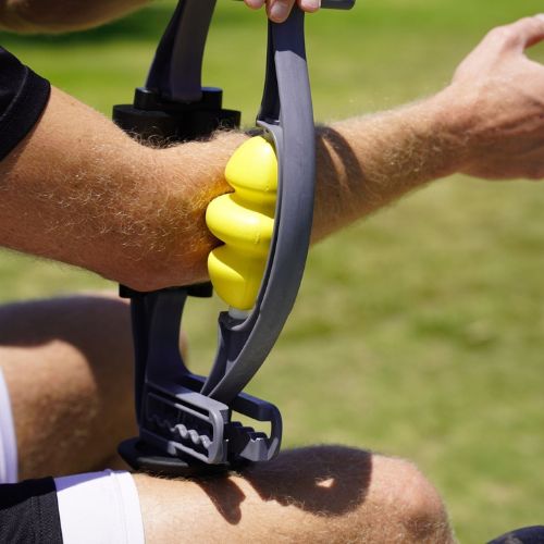 Person using a massage tool on their forearm outdoors.
