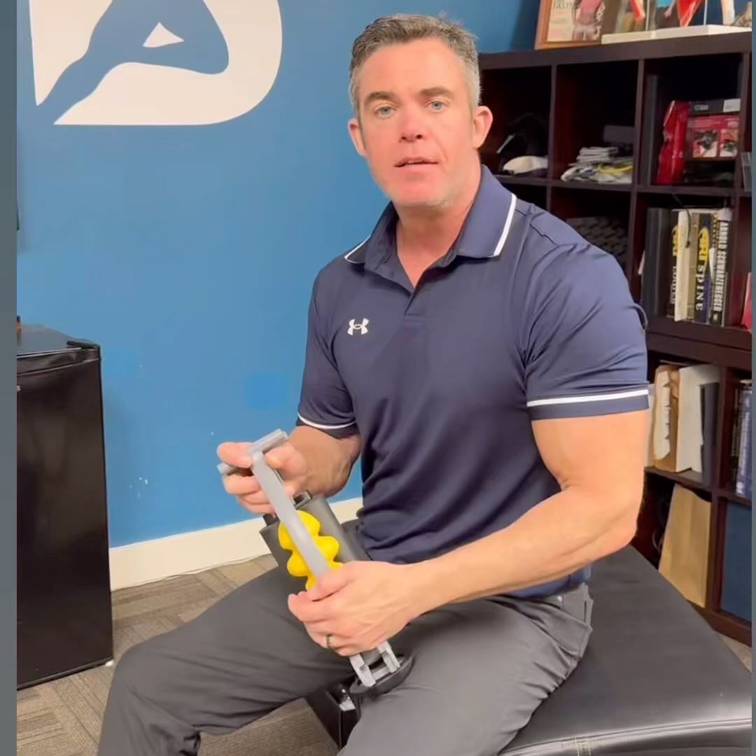 Man in a navy shirt holding a massage tool in an office setting.