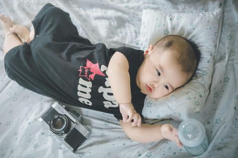 A camera and a milk bottle near a baby