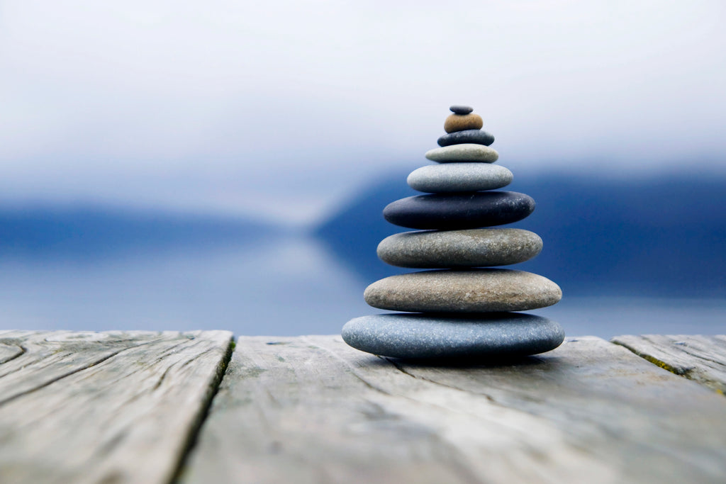 Achtsamkeit und Tee Achtsamkeitspraxis Steine gestapelt auf Holz Hintergrund blau und Meer Meditation