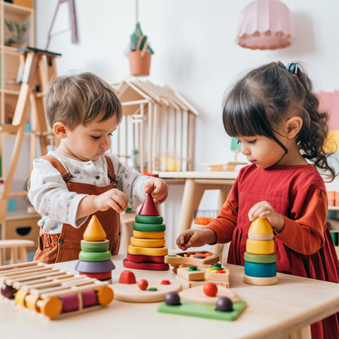 Zwei Kinder spielen im Klassenzimmer mit hölzernen Montessori-Spielzeugen