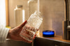 An image of a tap pouring bluewater in a reusable glass bottle