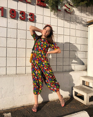 woman wearing black jumpsuit with multicolored floral print and black sandals