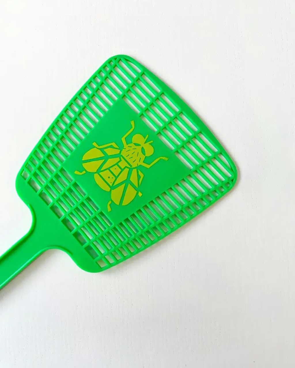 up close of green fly swatter with yellow fly logo in the middle