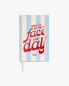 ivory and blue striped planner cover with "what do ya say we face the day" text graphic in metallic red and pink elastic band closure