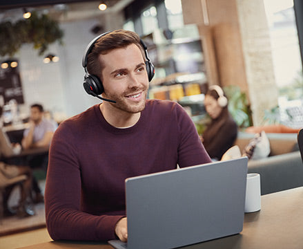 Smiling man using Jabra headset with laptop