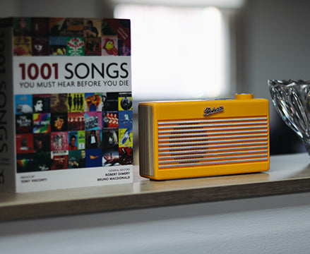 Yellow Roberts radio next to book on shelf