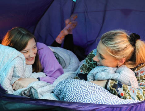 Two girls laughing inside purple tent