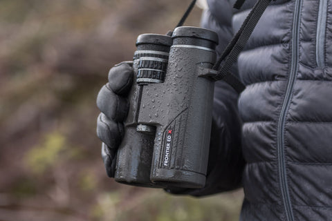 MAn wearing gloves holding Hawke Frontier binoculars