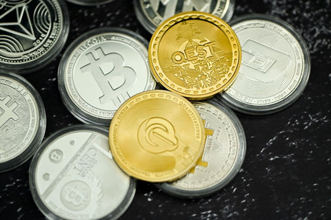 Assorted cryptocurrency coins with various symbols including Bitcoin and others, displayed on a dark surface, representing the diversity and physical representation of digital currencies.