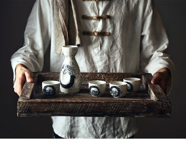 man holding a full sake set