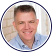 Smiling man in blue shirt with short hair.