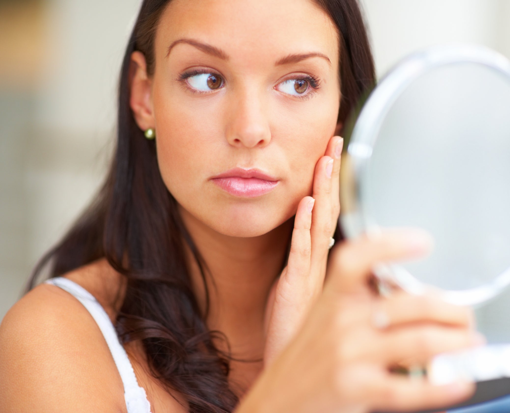 A woman with long brown hair looking in a mirror