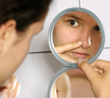 A girl looking on her nose in a mirror