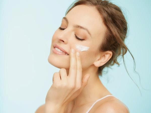 A woman smears her face with cream