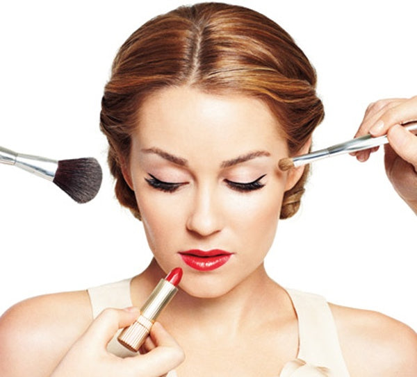 A woman with a lipstick and two brushes near her face