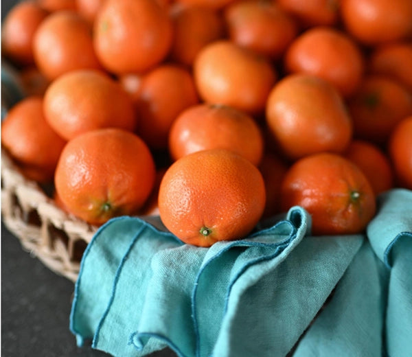 A close-up of a basket filled with oranges, captured by a Nikon NIKKOR Z 35mm f/1.4 lens.