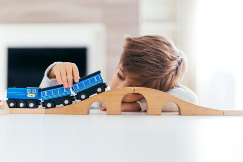 boy playing with train toy looking bored