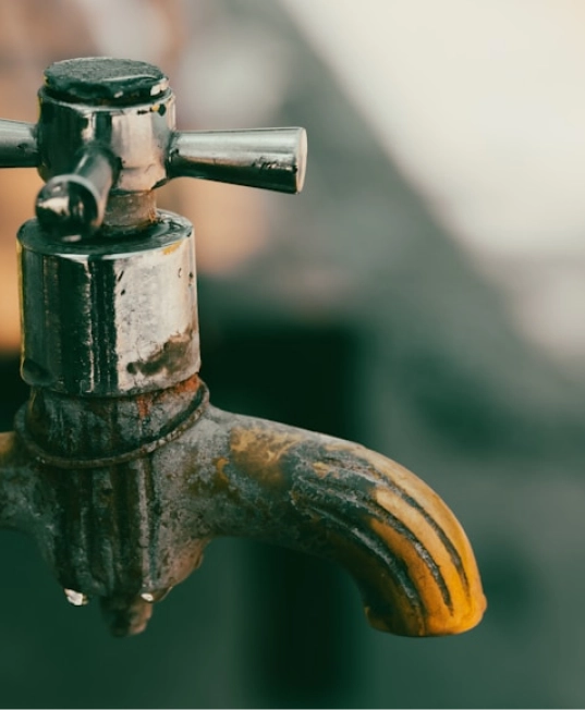 Close-up of a rusted outdoor water tap with a blurred background.