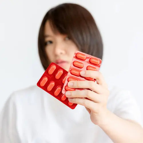 Woman holding medicine packs in front of camera