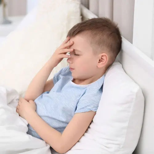 Child holding his head in pain in a sofa