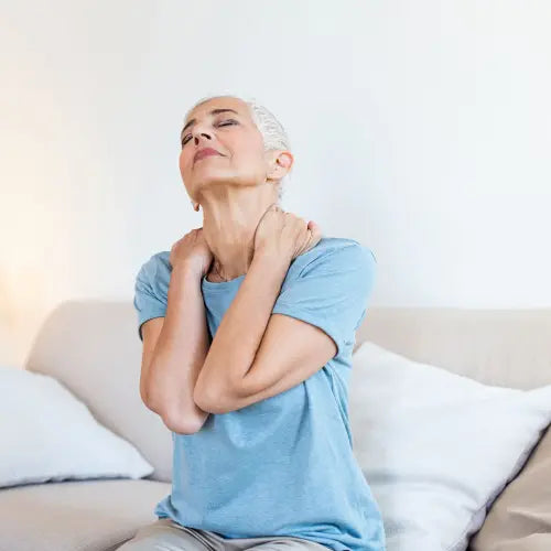 Femme assise sur un canapé se tenant la nuque 