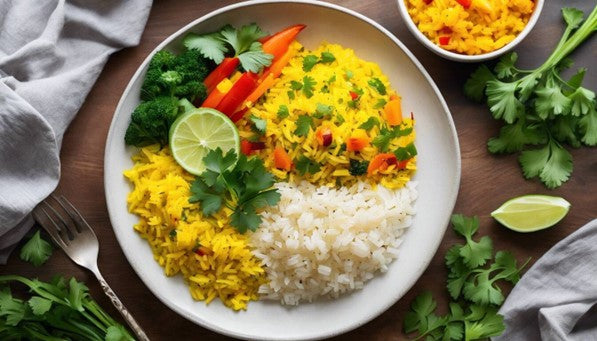 A plate of yellow turmeric rice with vegetables and lime on a wooden table.