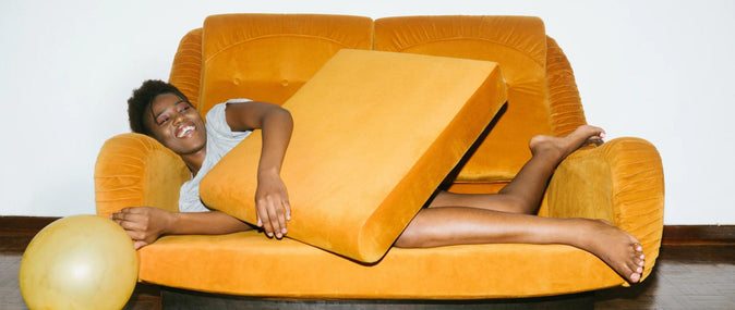 Uma mulher estirada em um sofá amarelo segurando um balão
