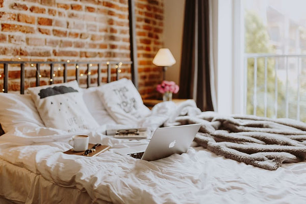 home office confortável sobre a cama com laptop, café e cadernos em um quarto aconchegante