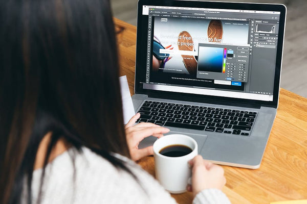 mulher tomando café e trabalhando em editor de imagem para inserir o layout depois em criador de sites