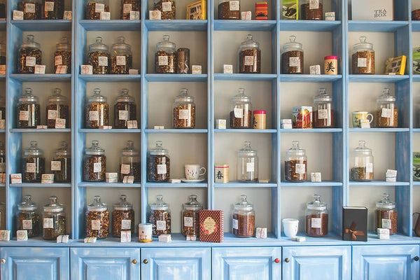 armário de loja de chás repleto de potes com ervas, xícaras e latas para venda