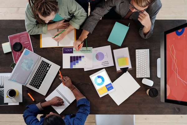 grupo em reunião de trabalho sobre trade marketing ao redor de uma mesa analisando gráficos